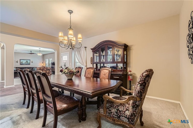 dining room featuring an inviting chandelier, arched walkways, baseboards, and light carpet