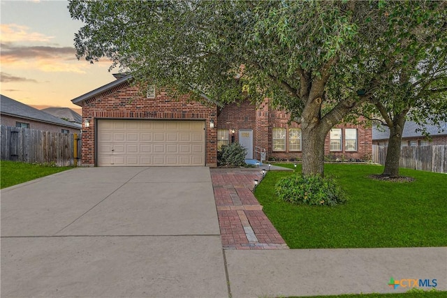 obstructed view of property with fence, brick siding, concrete driveway, an attached garage, and a yard