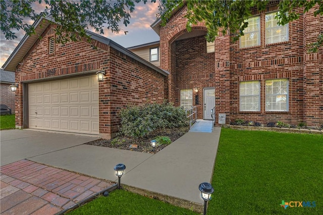 traditional-style home with a garage, driveway, a front lawn, and brick siding