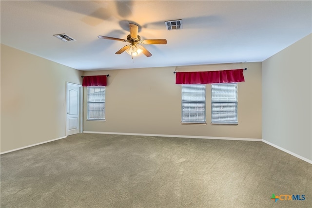 empty room featuring carpet, a ceiling fan, and visible vents