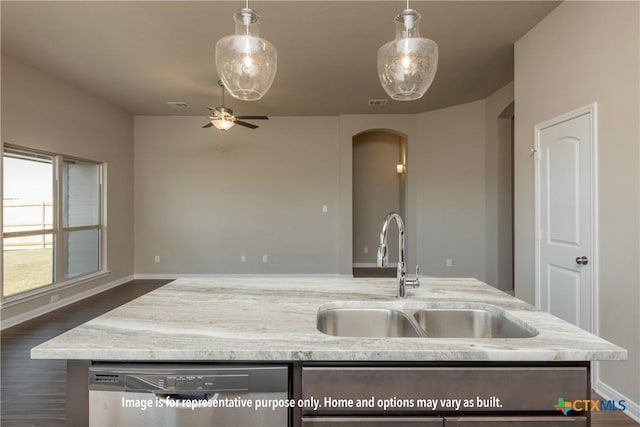 kitchen with light stone counters, open floor plan, stainless steel dishwasher, arched walkways, and a sink