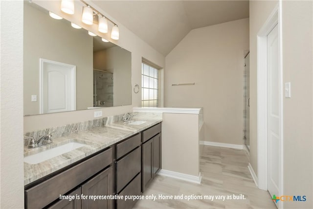 bathroom with double vanity, a sink, a stall shower, and lofted ceiling