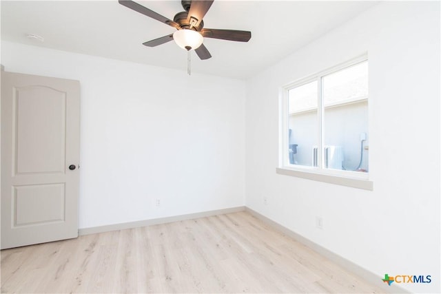 spare room with baseboards, ceiling fan, and light wood finished floors