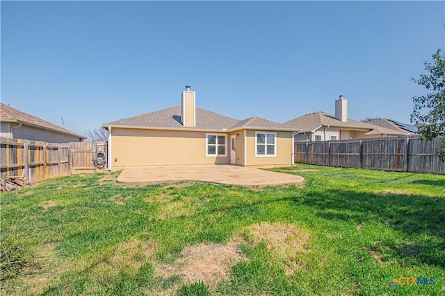 rear view of property featuring a fenced backyard, a chimney, a yard, a patio area, and stucco siding