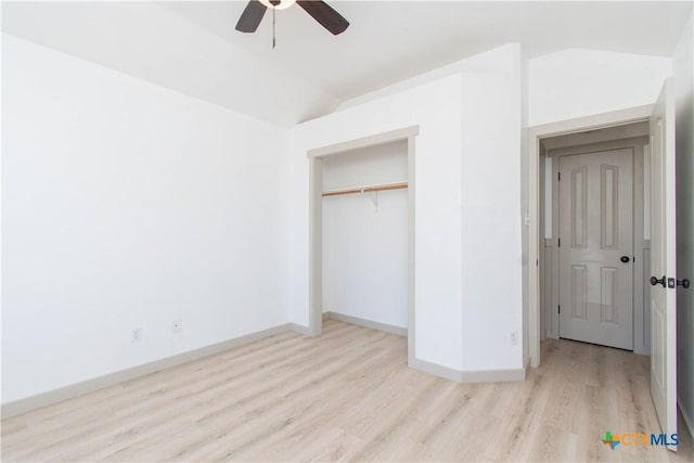 unfurnished bedroom with lofted ceiling, ceiling fan, light wood-style flooring, baseboards, and a closet