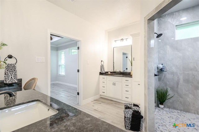 full bathroom with baseboards, a walk in shower, wood finished floors, and vanity