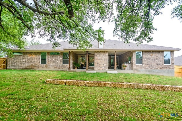 back of house featuring a lawn, fence, a patio area, and brick siding