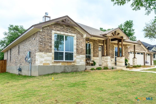 view of front facade featuring a chimney, a front yard, brick siding, and a garage