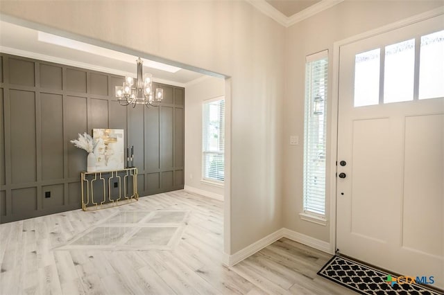 foyer featuring a wealth of natural light, a chandelier, a decorative wall, and ornamental molding