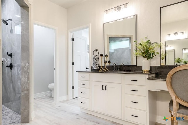 bathroom featuring toilet, walk in shower, and vanity
