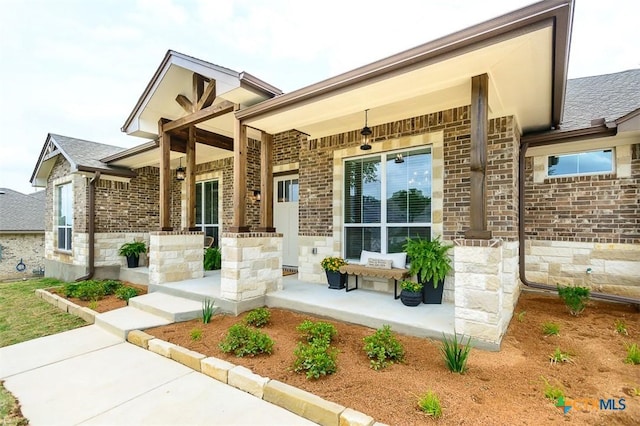 exterior space featuring covered porch, brick siding, and stone siding