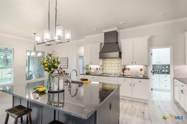 kitchen with a sink, an inviting chandelier, ornamental molding, custom exhaust hood, and stainless steel gas cooktop