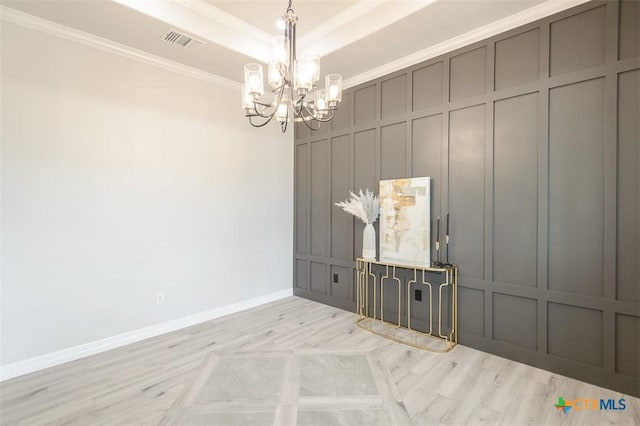 unfurnished room with a decorative wall, a chandelier, baseboards, visible vents, and crown molding