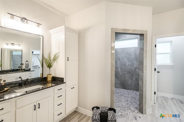 bathroom featuring walk in shower, vanity, and baseboards