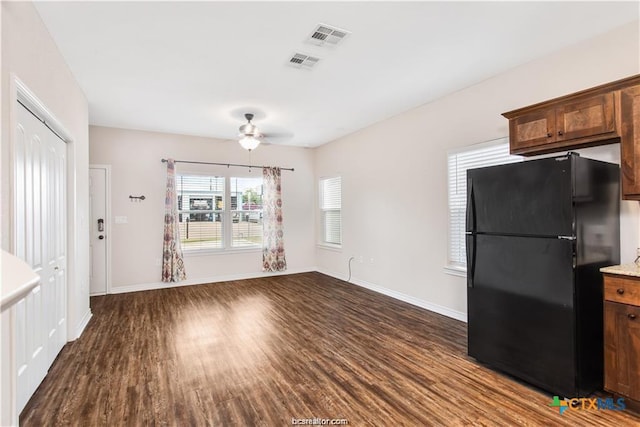 interior space featuring dark wood-style floors, baseboards, visible vents, and freestanding refrigerator