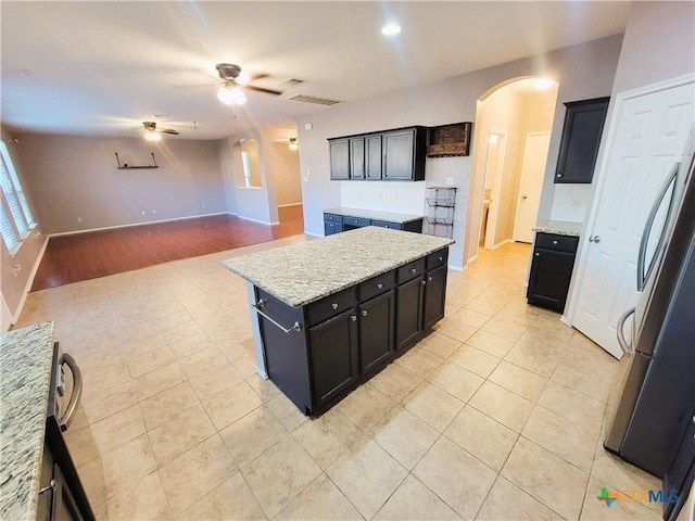 9200 Ashlyn Dr, Killeen, TX 76542 - kitchen with arched walkways, a ceiling fan, fridge, light tile patterned flooring, and dark cabinets