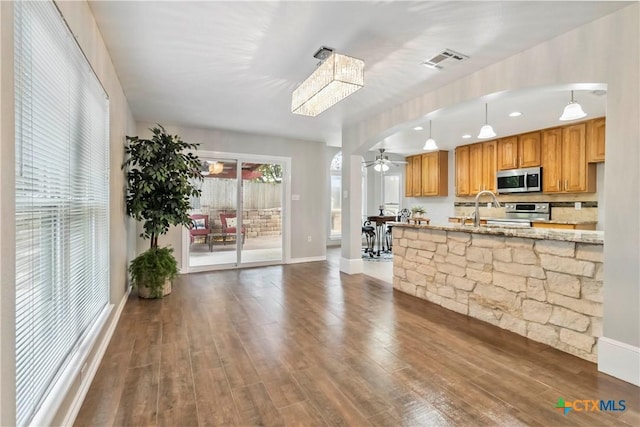 2652 Poplar Grove Ln, Schertz, TX 78154 - kitchen featuring stainless steel appliances, wood finished floors, light stone countertops, decorative light fixtures, and brown cabinets
