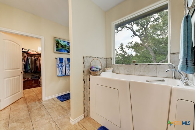 bathroom with a wealth of natural light, a tub, and tile patterned flooring