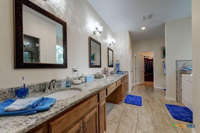 861 Rutherford, Fischer, TX 78623 - bathroom with double vanity, tile patterned flooring, a walk in closet, and baseboards