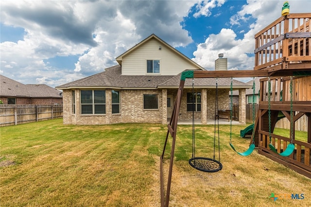 rear view of house featuring a playground and a yard