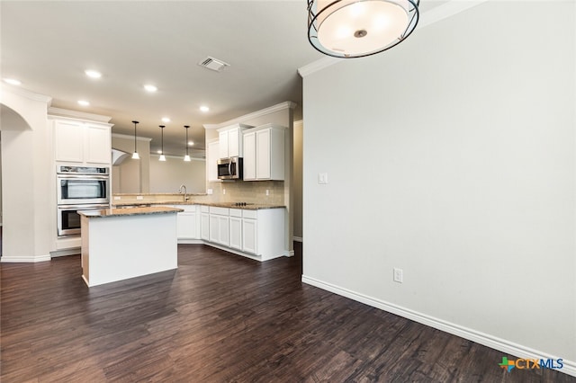 kitchen featuring stainless steel appliances, hanging light fixtures, dark hardwood / wood-style floors, and a center island