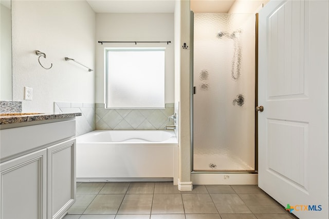 bathroom featuring shower with separate bathtub, vanity, and tile patterned floors