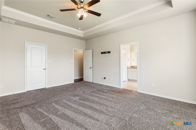 unfurnished bedroom featuring crown molding, connected bathroom, a tray ceiling, light colored carpet, and ceiling fan