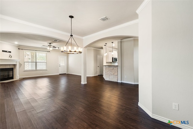 unfurnished living room with ceiling fan with notable chandelier, dark wood-type flooring, and crown molding