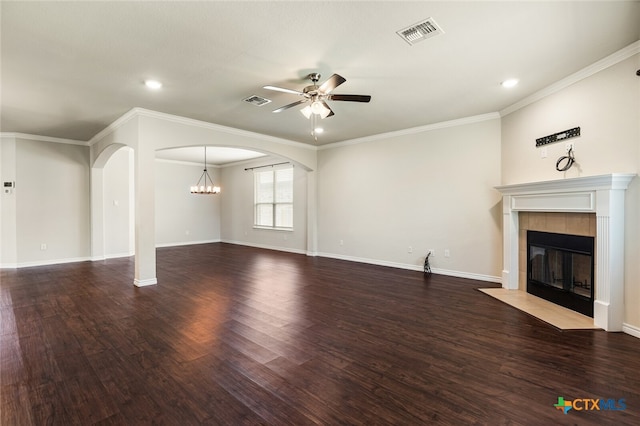 unfurnished living room with ceiling fan with notable chandelier, a tile fireplace, dark hardwood / wood-style flooring, and crown molding