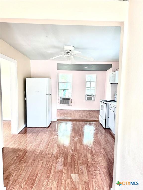 kitchen featuring a ceiling fan, wood finished floors, cooling unit, white appliances, and baseboards