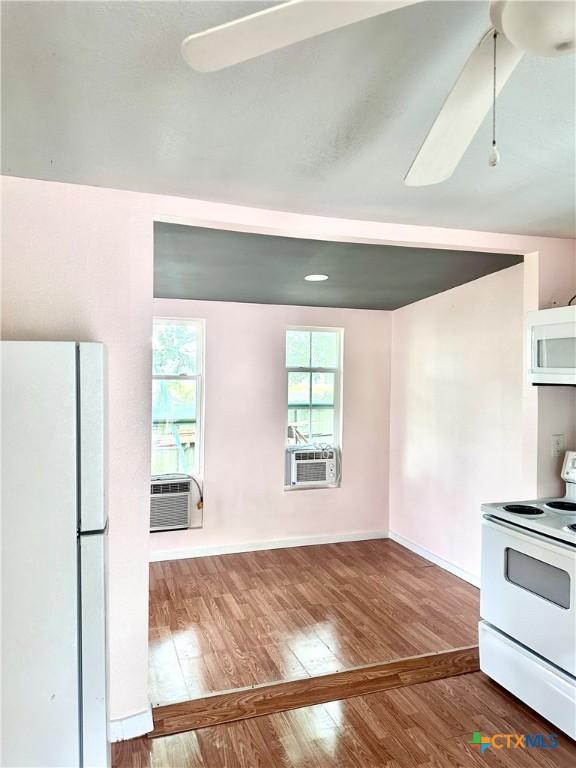 kitchen with white appliances, baseboards, a ceiling fan, hardwood / wood-style flooring, and cooling unit