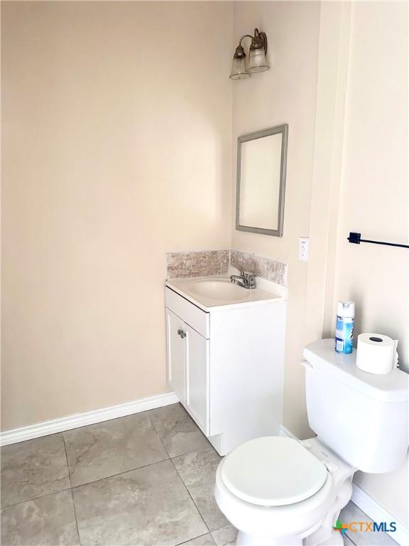 bathroom featuring baseboards, vanity, toilet, and tile patterned floors