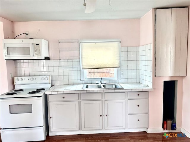 kitchen with tile countertops, white appliances, backsplash, and a sink