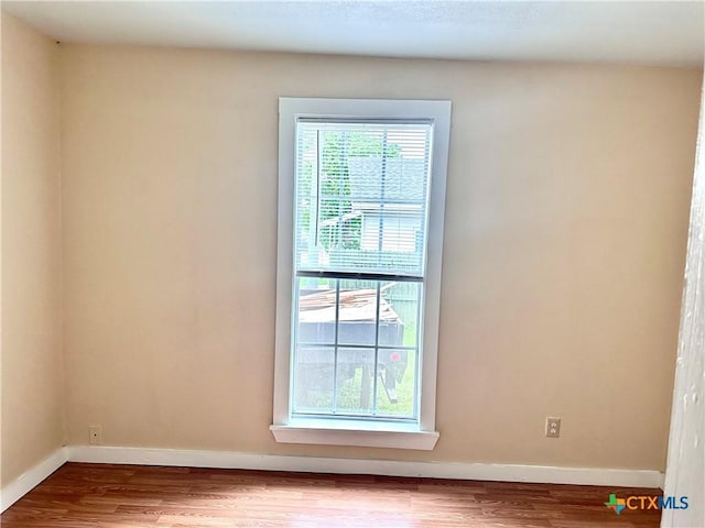 spare room with baseboards and wood finished floors