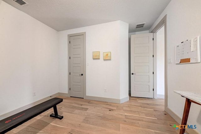 workout area with baseboards, light wood-style floors, and visible vents