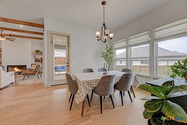 dining room featuring light wood finished floors, ceiling fan with notable chandelier, and a large fireplace