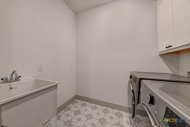 washroom featuring independent washer and dryer, cabinet space, light floors, and baseboards