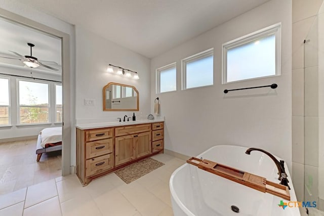 ensuite bathroom with a freestanding tub, ceiling fan, vanity, and a healthy amount of sunlight