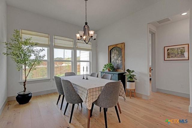 dining space featuring baseboards, visible vents, an inviting chandelier, and light wood finished floors
