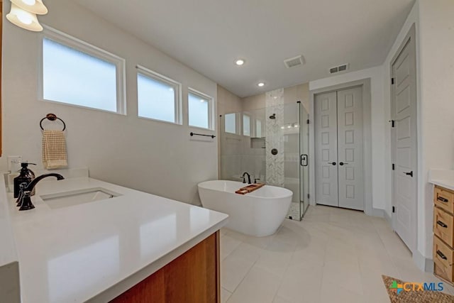 bathroom featuring a closet, visible vents, a shower stall, a freestanding tub, and vanity