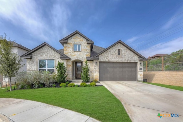 view of front facade with stone siding, an attached garage, a front yard, and driveway