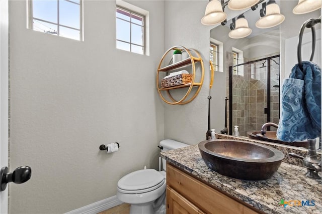 full bath with toilet, a shower stall, vanity, and baseboards