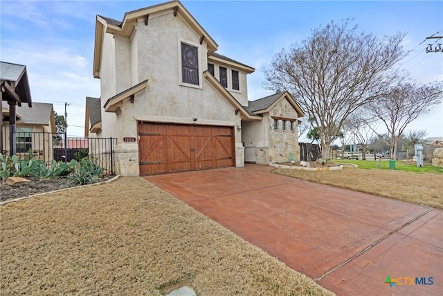 view of front of property featuring a garage, fence, stone siding, driveway, and stucco siding