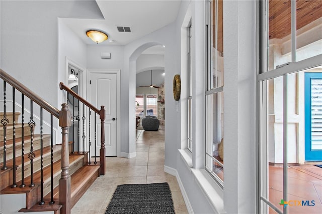 entryway with arched walkways, visible vents, light tile patterned flooring, baseboards, and stairs