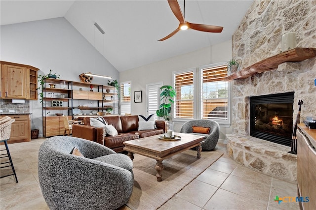 living room featuring ceiling fan, high vaulted ceiling, a stone fireplace, and light tile patterned flooring