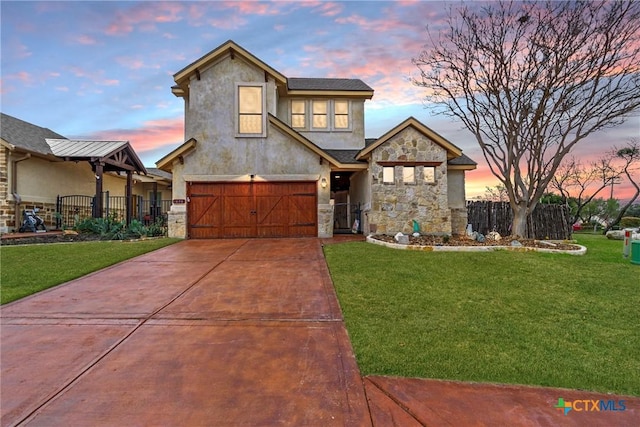 view of front of home featuring a garage, concrete driveway, stone siding, fence, and a yard