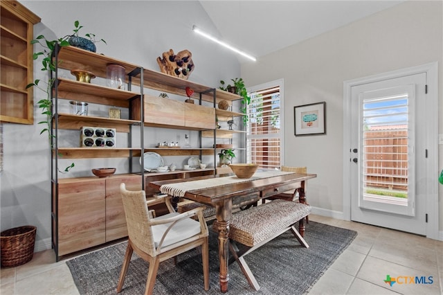 dining space with light tile patterned floors, lofted ceiling, a wealth of natural light, and baseboards