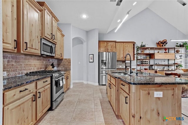 kitchen with stainless steel appliances, light tile patterned flooring, vaulted ceiling, a sink, and dark stone counters