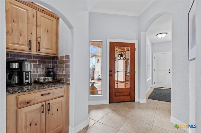 entrance foyer featuring plenty of natural light, arched walkways, and crown molding