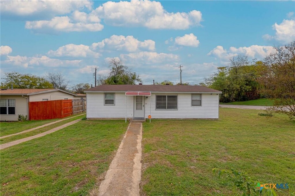 view of front of home with fence and a front lawn